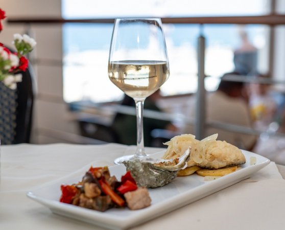 Calice di vino bianco accanto a un piatto di antipasti.