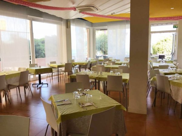 Sala da pranzo luminosa con tavoli apparecchiati.