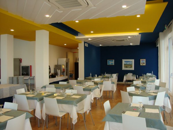 Ristorante con tavoli apparecchiati e soffitto colorato.