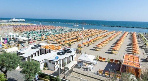 Una spiaggia con numerosi ombrelloni a righe colorate.