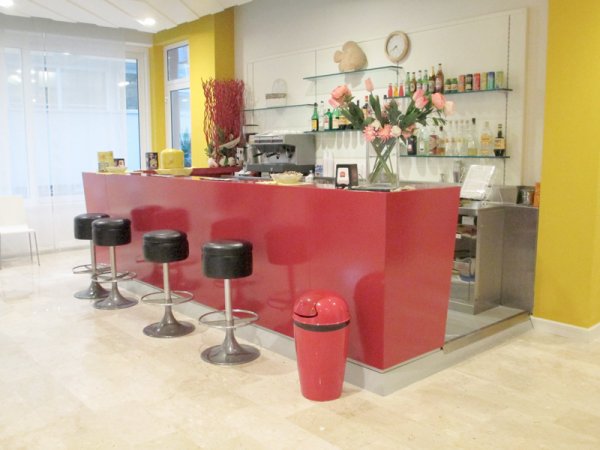 Bancone bar rosso con sgabelli neri e decorazioni.