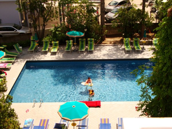 Piscina con lettini e ombrelloni verde e giallo.