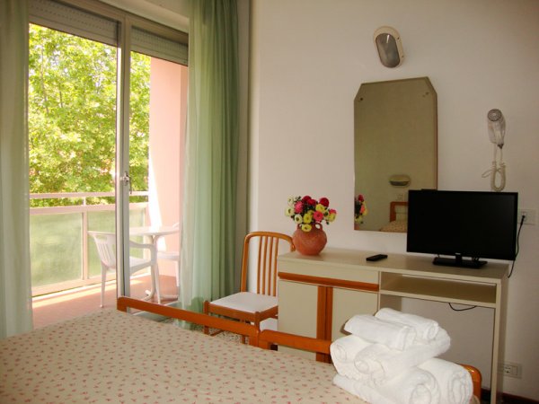 Camera con letto, TV, specchio e balcone.
