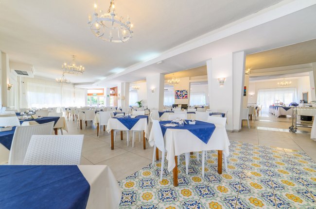 Sala pranzo luminosa con tovaglie bianche e blu.