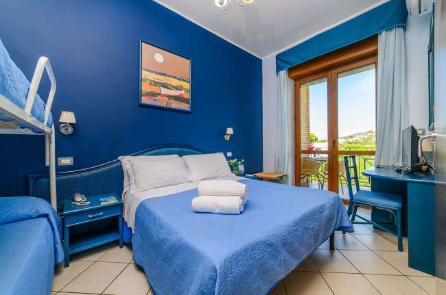 Camera blu con letto matrimoniale e balcone.