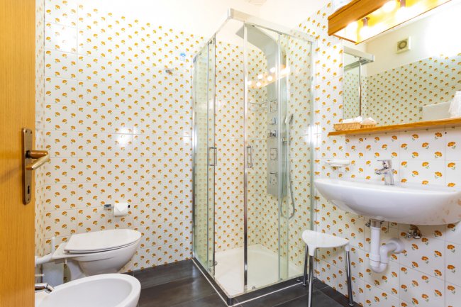 Bagno con doccia in vetro, lavabo e bidet.