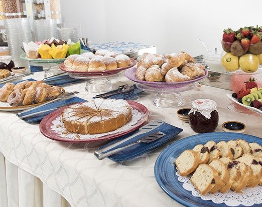 Buffet con dolci assortiti, torte e frutta su un tavolo imbandito.