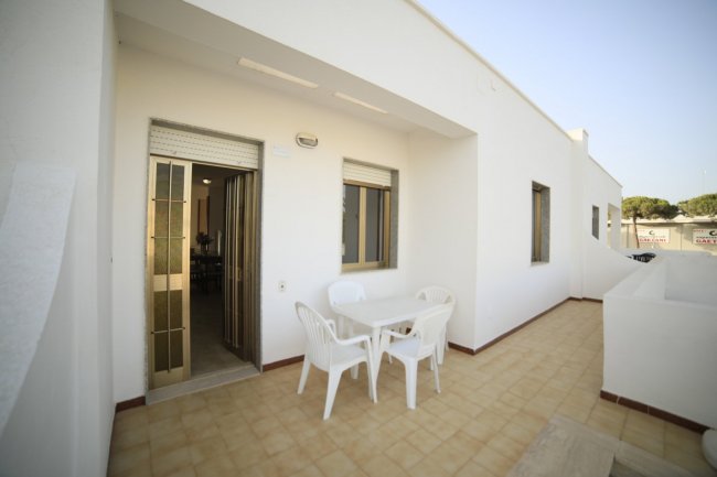 Terrazza con tavolino e sedie bianche.