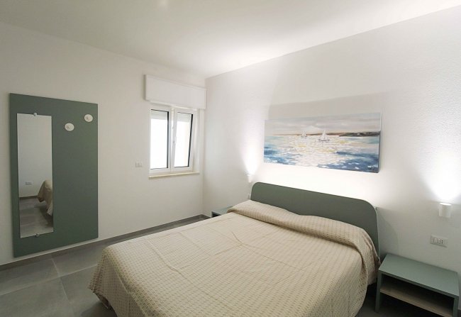 Camera da letto con letto matrimoniale e dipinto nautico.