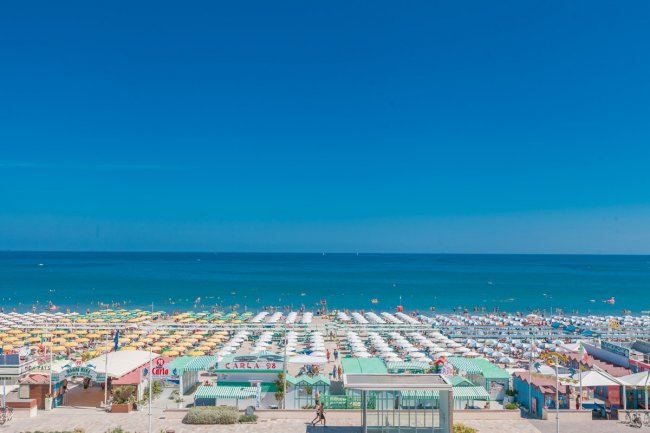 Una spiaggia con ombrelloni colorati e mare blu.