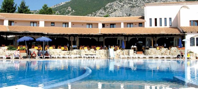 Complesso alberghiero con piscina e montagne sullo sfondo.