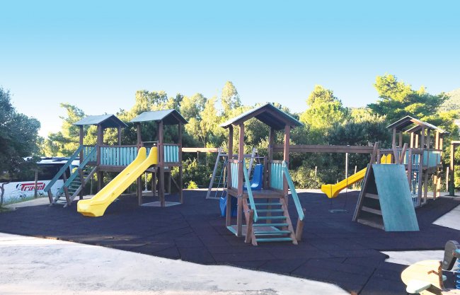 Parco giochi con scivoli gialli su pavimento morbido.