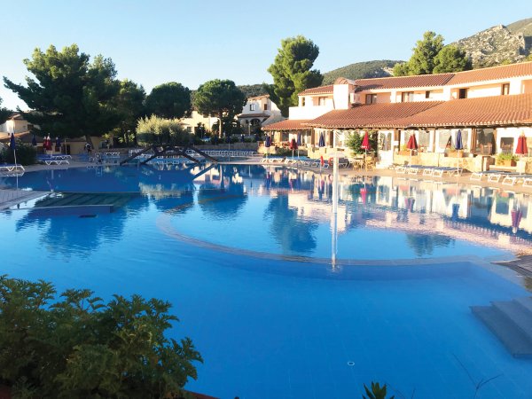 Ampia piscina con ponticello e edificio sullo sfondo.