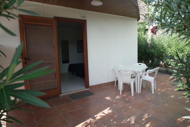 Ingresso con porta aperta, tavolo e sedie esterni.