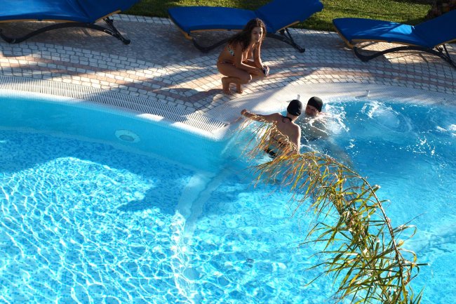 Due bambini e una donna vicino a una piscina.
