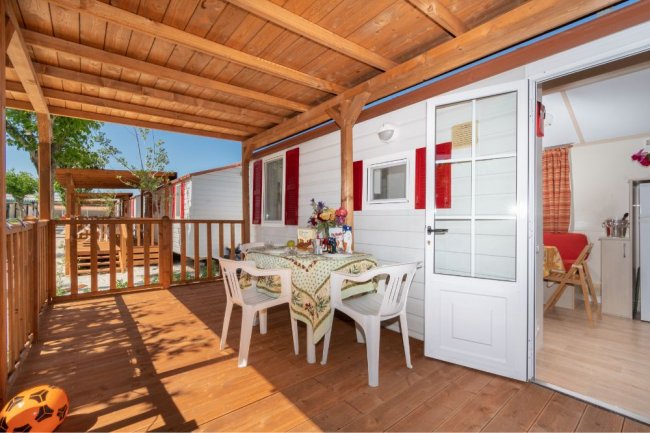 Veranda con tavolo, sedie bianche e arredo variopinto.