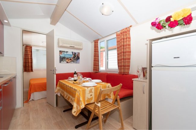 Interno con tavolo apparecchiato, divano rosso e finestra luminosa.