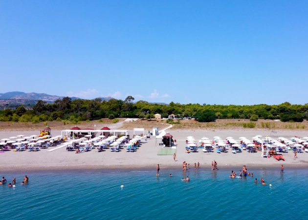Spiaggia con ombrelloni e persone in acqua.