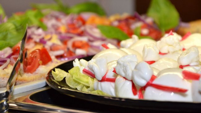 Piatto di mozzarella decorata con verdure fresche.