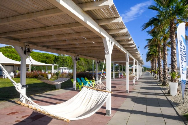 Pergolato con amache e sedie lungo un viale.