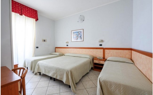 Camera d'albergo con tre letti, due singoli e uno matrimoniale.