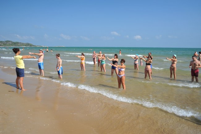 Persone fanno esercizi nell'acqua sulla spiaggia.