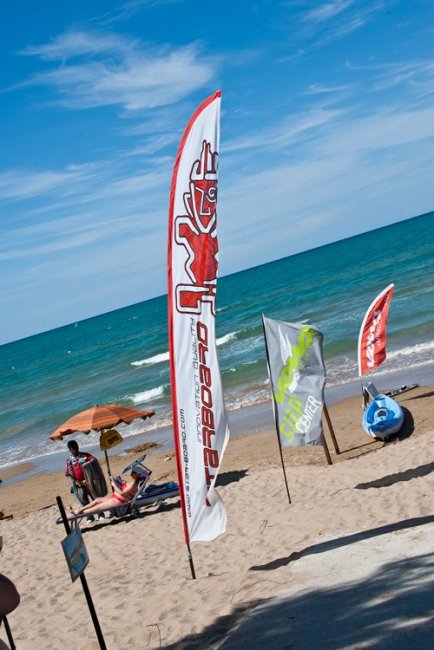 Spiaggia con bandiere e mare al sole.