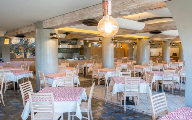 Sala da pranzo con tavoli apparecchiati.