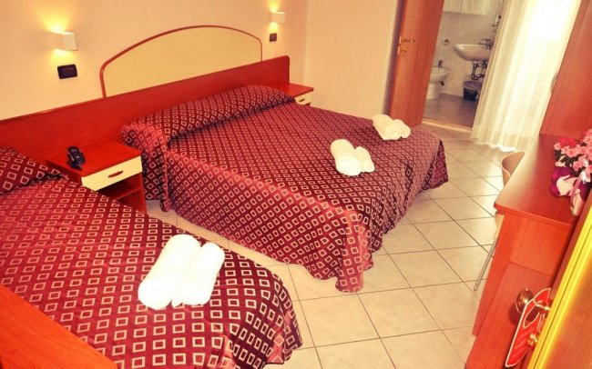 Camera d'albergo con due letti matrimoniali.