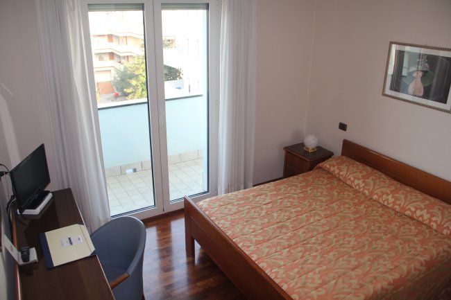 Camera da letto con letto matrimoniale e balcone.