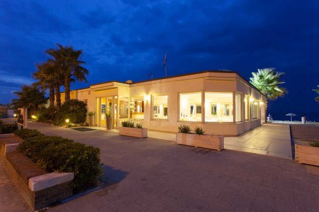 Edificio illuminato di notte, circondato da palme.