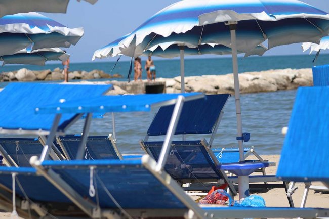 Lettini blu e ombrelloni in spiaggia.