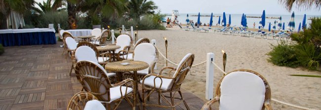 Terrazza sulla spiaggia con tavolini e sedie.