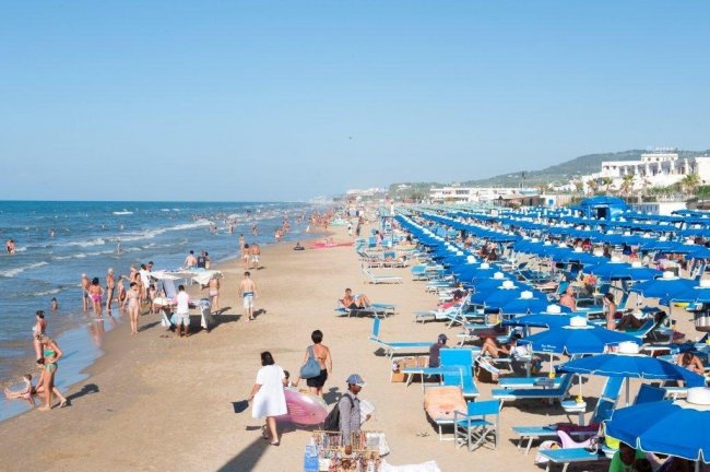 Spiaggia affollata con ombrelloni blu.
