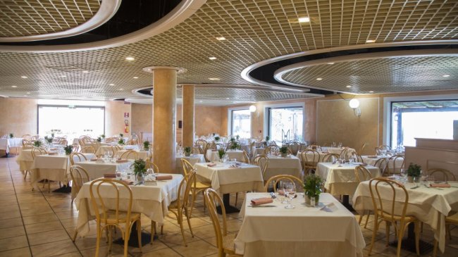 Ristorante con tavoli apparecchiati e sedie di legno.