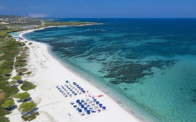 Spiaggia di sabbia bianca con ombrelloni e mare cristallino.